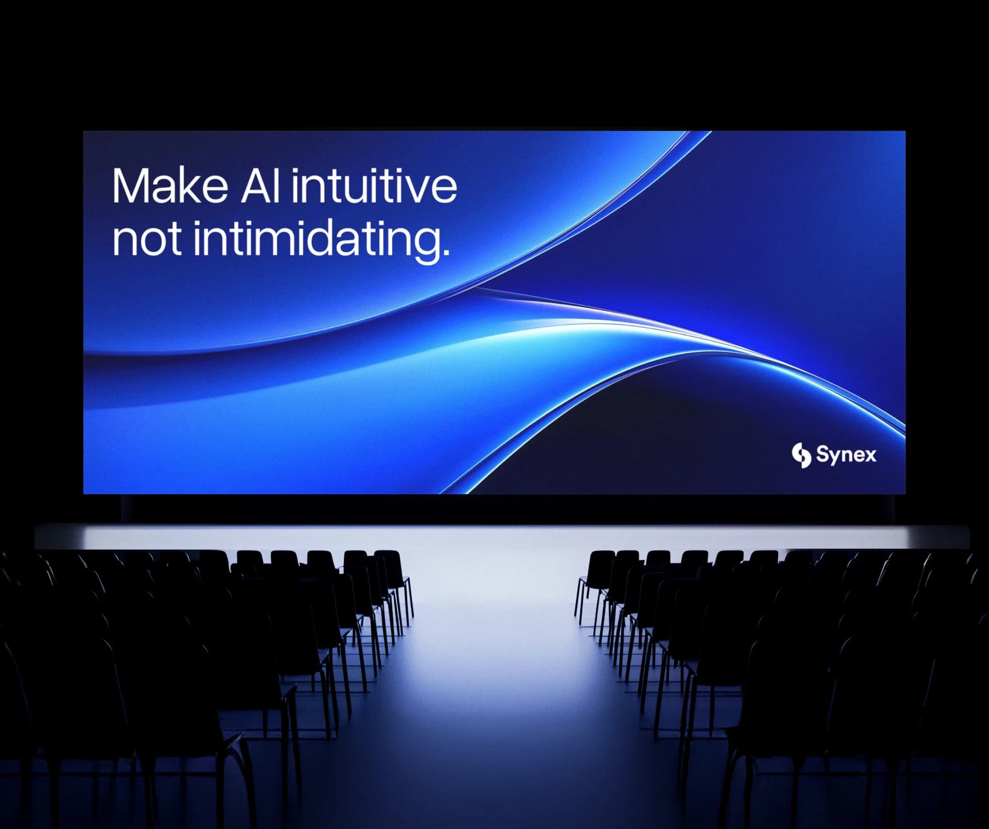An empty auditorium facing a large screen that reads Make AI intuitive, not intimidating.
