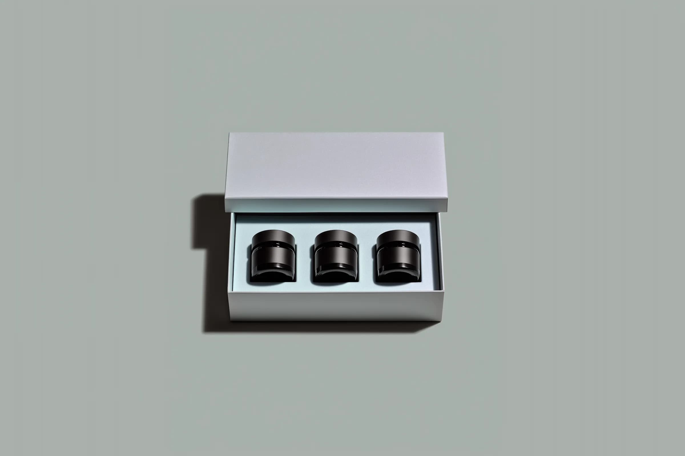 Three black jars set in an open grey presentation box.
