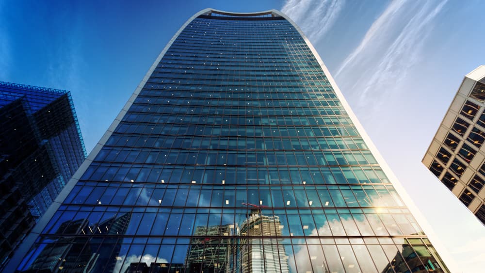 A curved glass office tower against a blue sky